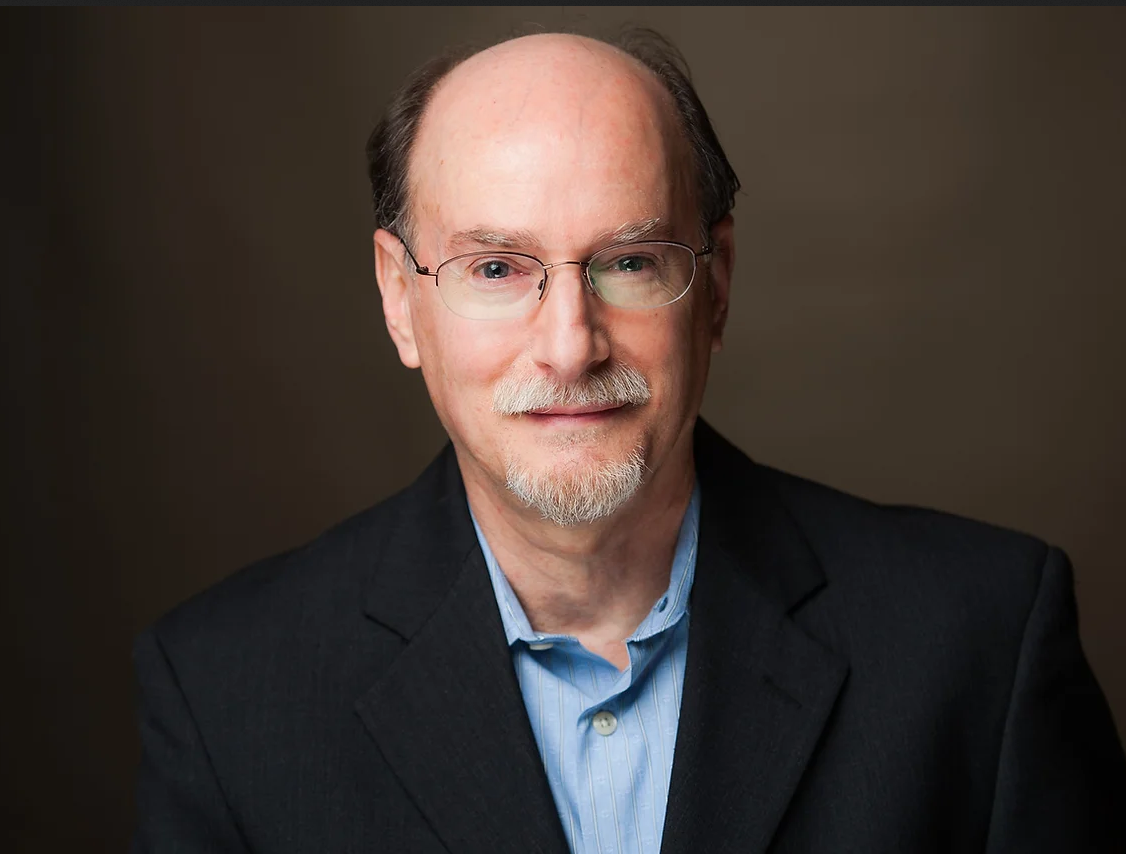 Photo of Dean Radin with a neutral brown background